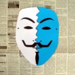 Zweifarbig zerissenes Guy Fawkes Maske auf Zeitungspapier