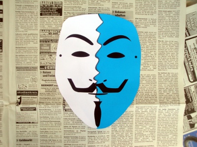 Zweifarbig zerissenes Guy Fawkes Maske auf Zeitungspapier
